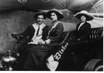 A studio portrait of a man in the driver's seat with two unknown female passengers. The vehicle has a Bisbee pennant.