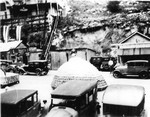 Bisbee's 50th birthday celebration parade in 1931. The float is of a woman's large dress, with the woman on top. The float on the far left behind the woman reads, Girl Reserves. Cars are parked on the side of the road.