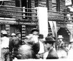 Main Street on pay day. Photo dated 1908. This is the east face of the present library/post office building. The opening behind the man on the far right is the entrance to the post office. Note Post Office carved into the stone above the entrance.