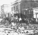 Main Street buildings after the 1908 in Bisbee. Right to left: Bank of Bisbee, Rineharts Drugs, Gilman Jewelry, Miner's and Merchant's Bank, and Bisbee Drug. Debris is scattered throughout the street. An unidentified man is on horseback.