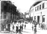 Main Street, Bisbee street scene, circa 1905, at the time of construction of the post office/library. The Bank of Bisbee sign had not been changed. The bank on the west end is under construction. Entrance facade is yet to be enlarged to present site. Unknown what event is taking place on the left side of the photo.