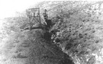A man riding on a tramway bucket between Shattuck Mine and ore bins at the railroad in Bisbee.