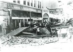Main Street, Bisbee after the flood of 1908. Debris is scattered and piled up on Main Street. The Royal Theater middle right. A sign for the Bisbee Drug Company can be seen in upper right.