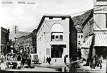 Photograph of the mouth of Brewery Gulch showing one of the many faces of the Orpheum Theater in 1910. There are many people and wagons in the street. There is a large puddle in front of the theater and Review Avenue.